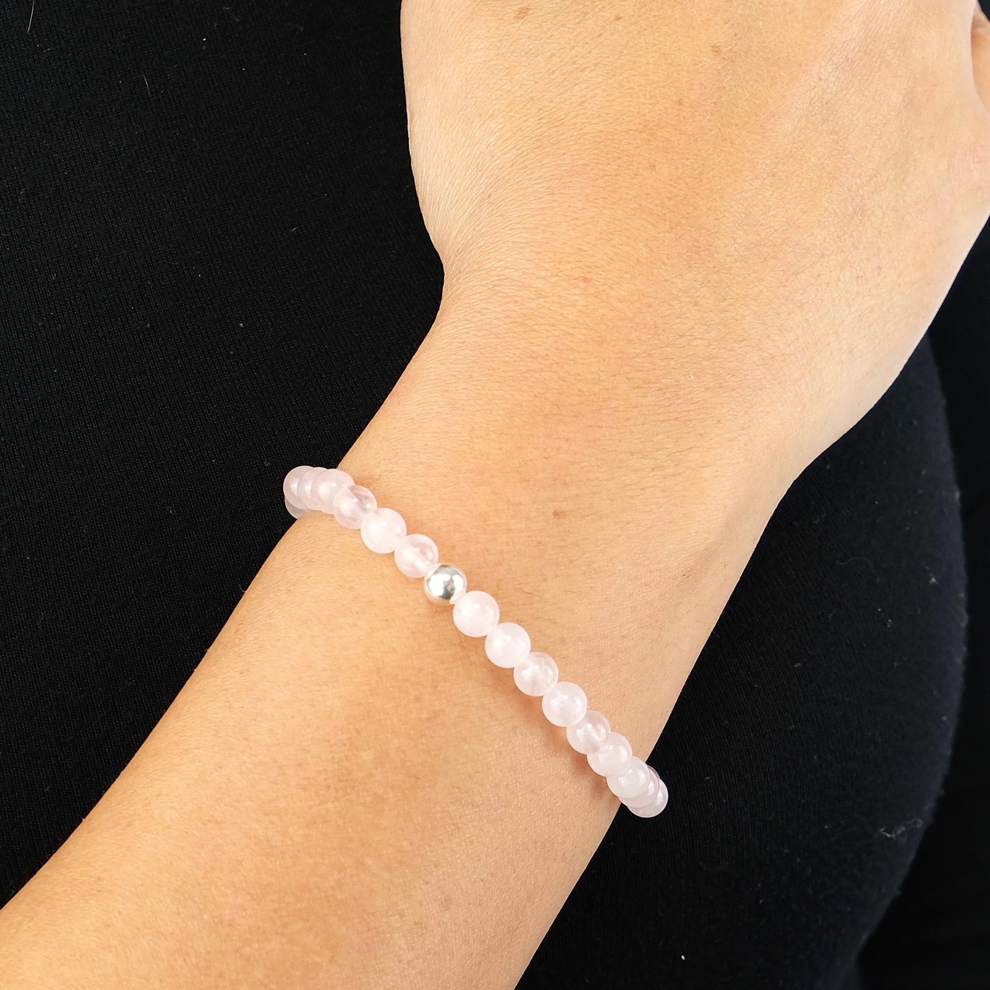 Rose Quartz gemstone bracelet in 6mm beads with 925 sterling silver accent worn on the model's wrist.