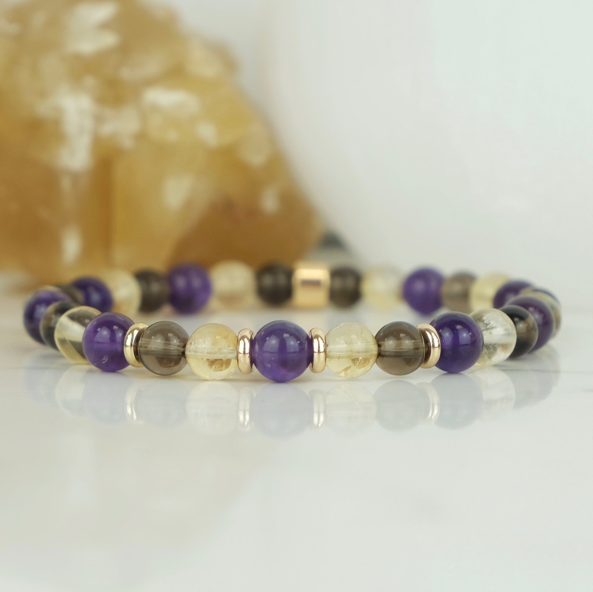 An Amethyst, citrine and smoky quartz gemstone bracelet in 6mm beads with gold accessories