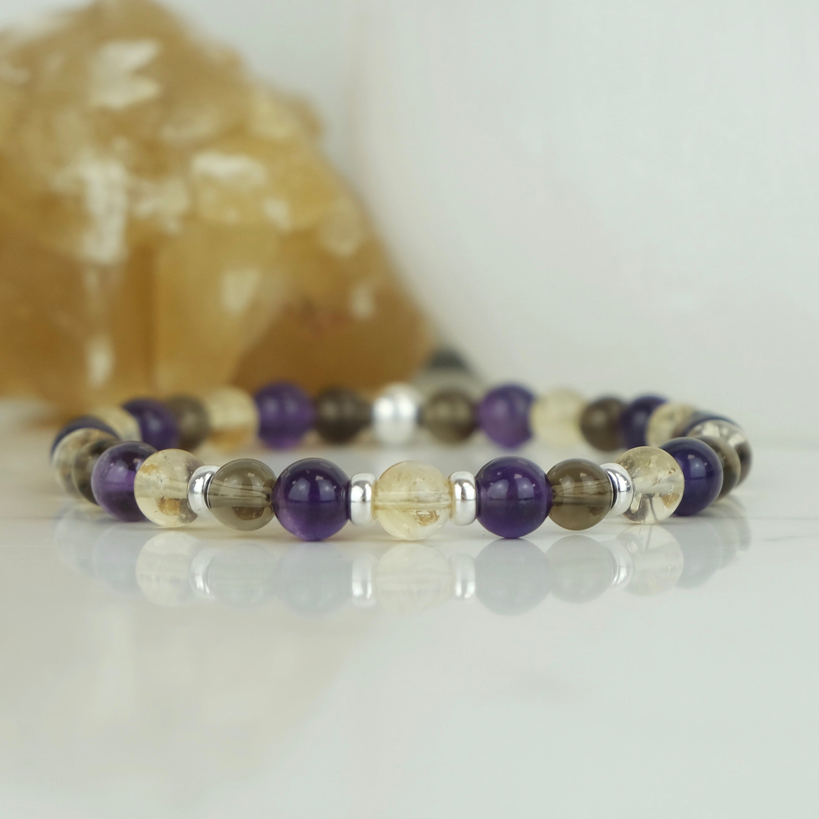 An Amethyst, citrine and smoky quartz gemstone bracelet in 6mm beads with silver accessories