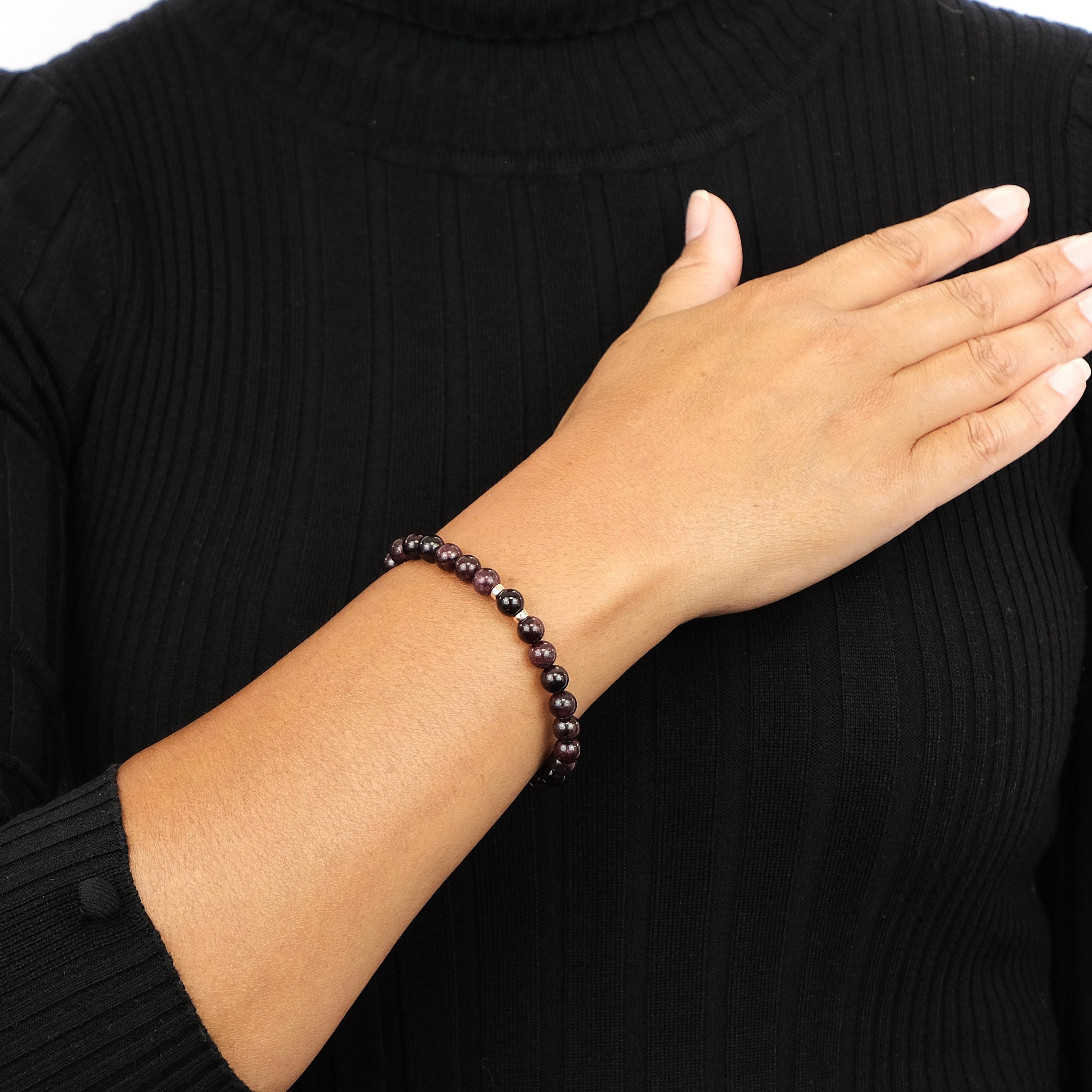 A model wearing A garnet gemstone bracelet in 6mm beads with gold filled accessories