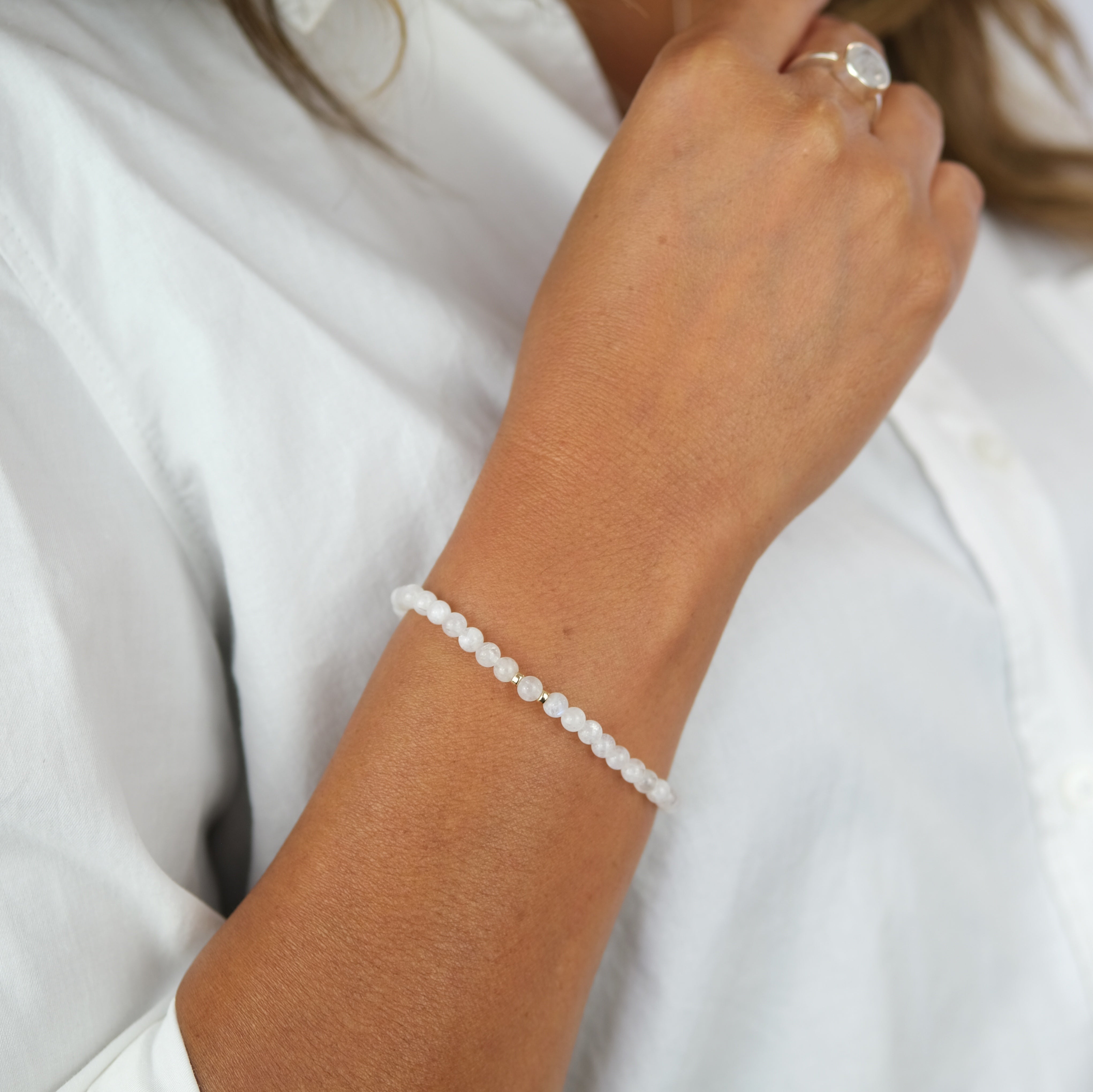 A model wearing A moonstone gemstone bracelet in 4mm beads with gold filled accessories
