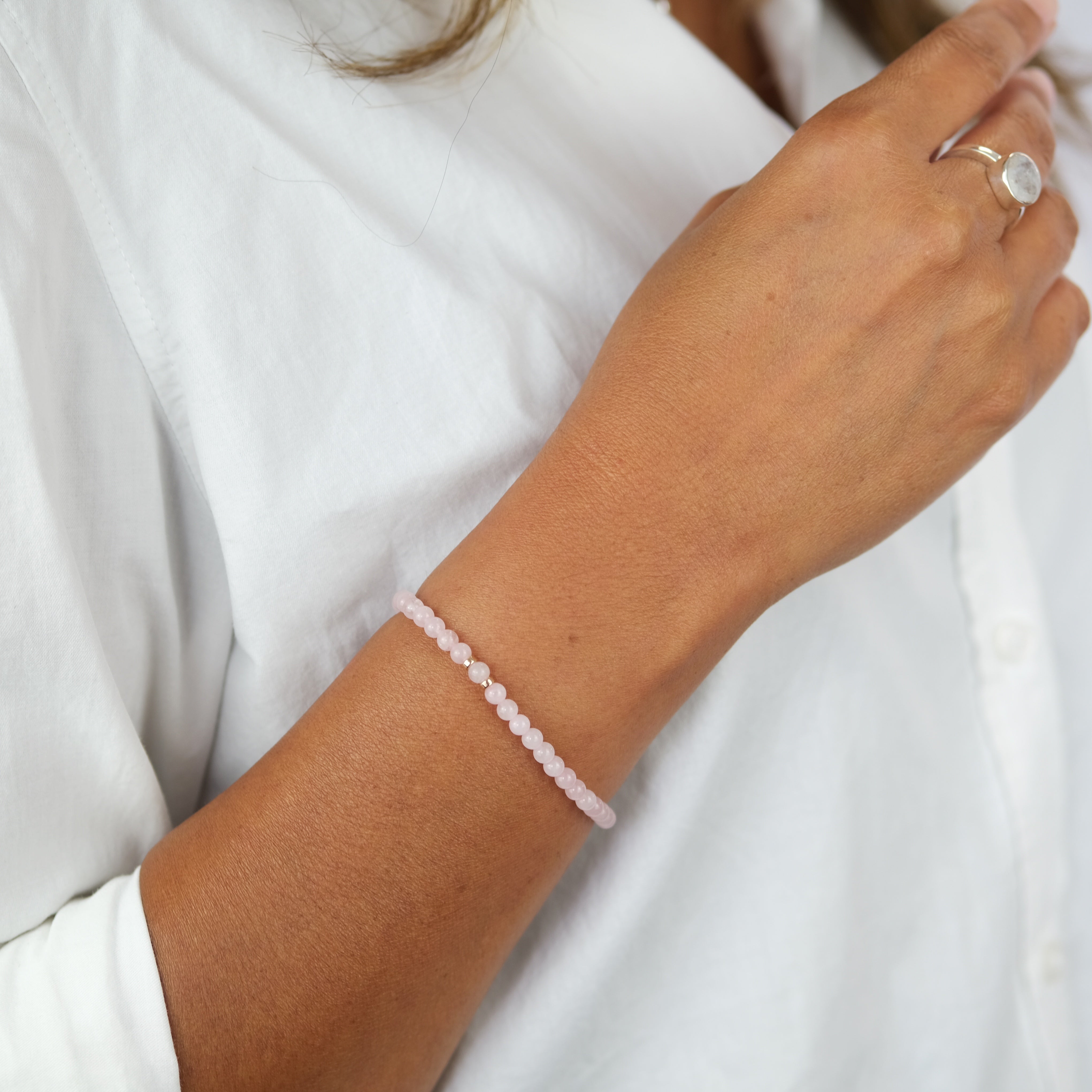 A model wearing A rose quartz gemstone bracelet in 4mm beads with gold filled accessories